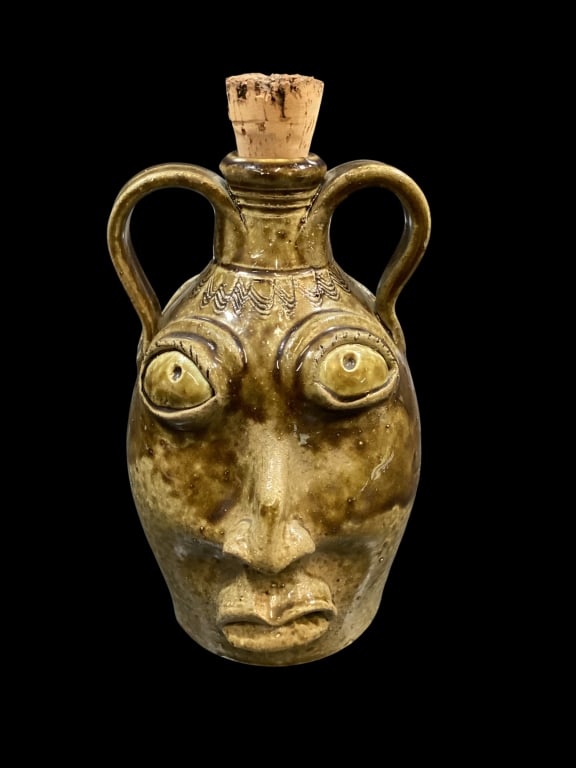 Rodney Leftwich Double Face Jug: Southern Folk pottery stoneware ugly face jug, 9 inches tall, double sided face, runny alkaline glaze, loop handles, white clay teeth. Expressive faces both sides pronounced nose, buggy eyes. Leftwich