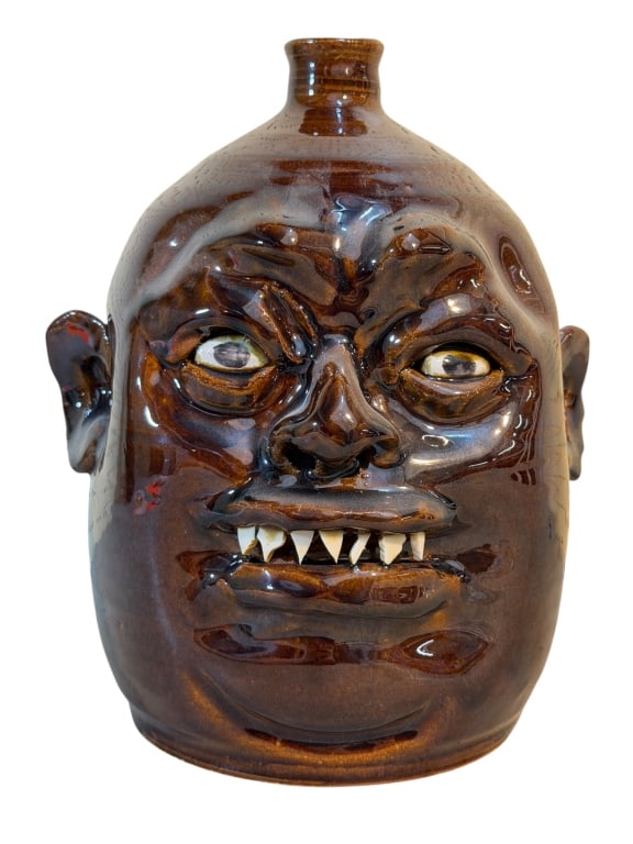 Marvin Bailey Face Jug: Southern folk art face jug by South Carolina potter Marvin Bailey. The jug has a smooth, rounded body with a flared spout and a rich, glossy tobacco-brown glaze that pools around the sculpted