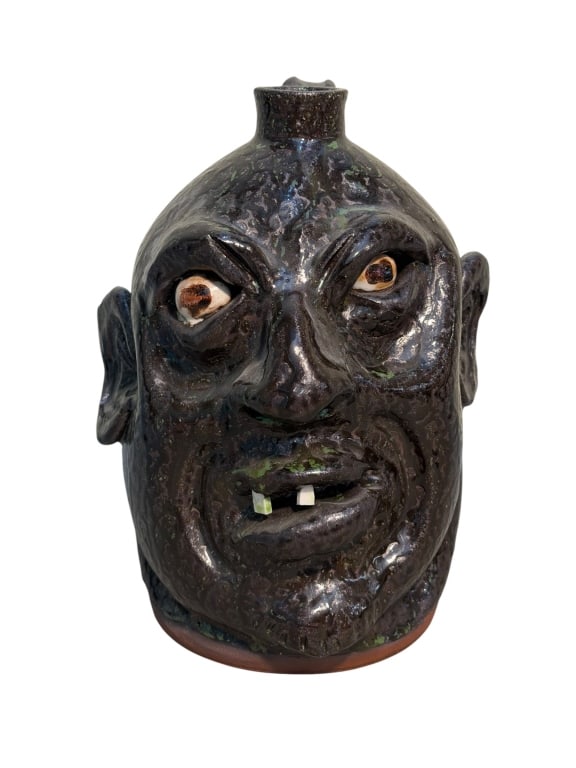 Marvin Bailey Face Jug: Southern folk art face jug by South Carolina potter Marvin Bailey. The jug features a metallic dark bronze-black glaze with subtle green iridescence across its textured surface. Hand-painted eyes with