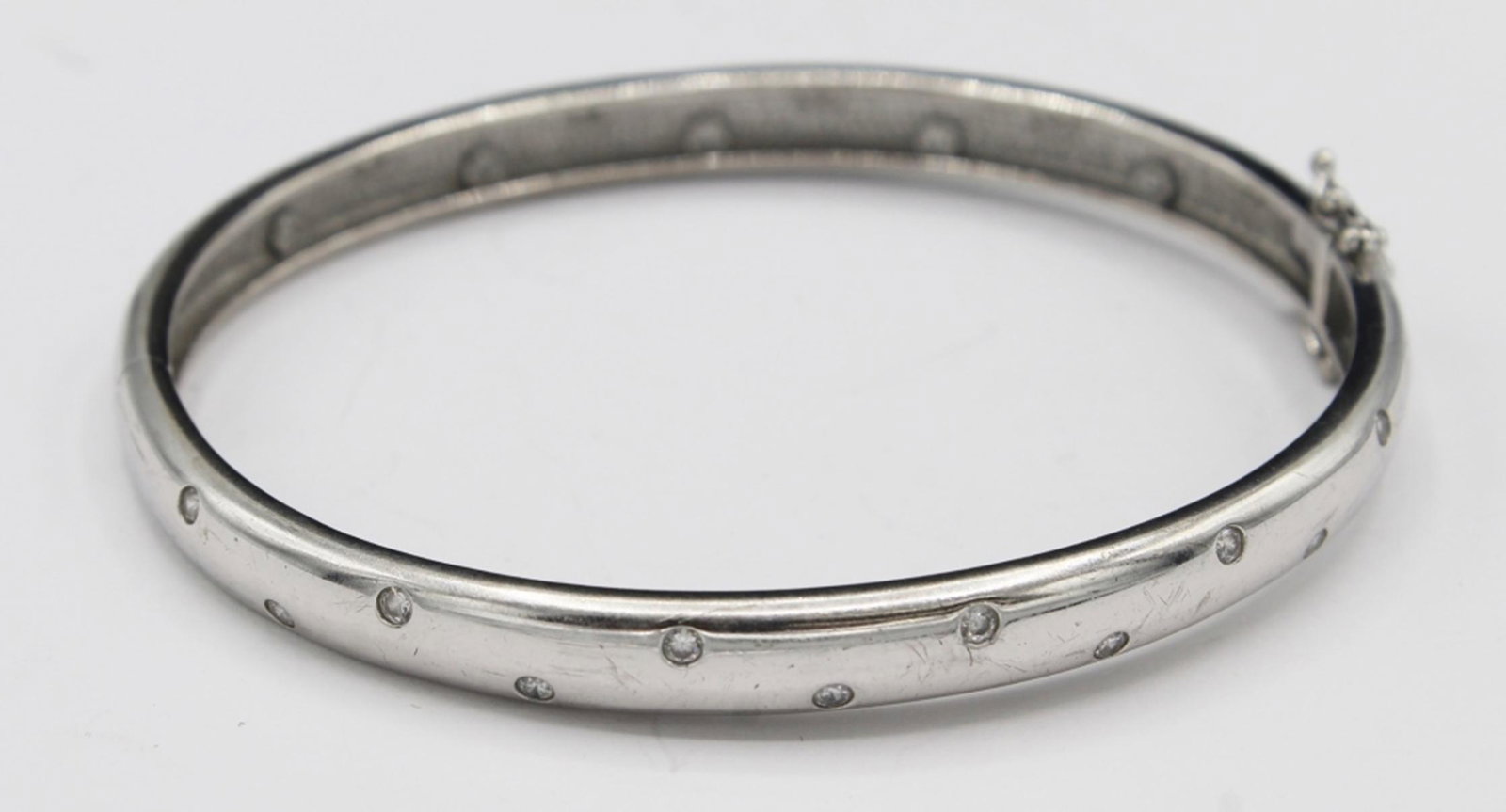 STERLING SILVER BANGLE BRACELET: MADE IN CHINA. CZ ACCENTS WITH CLASP CLOSURE. 3" DIAMETER. TOTAL WEIGHT 23.7 GRAMS. ESTIMATE: $30-$50