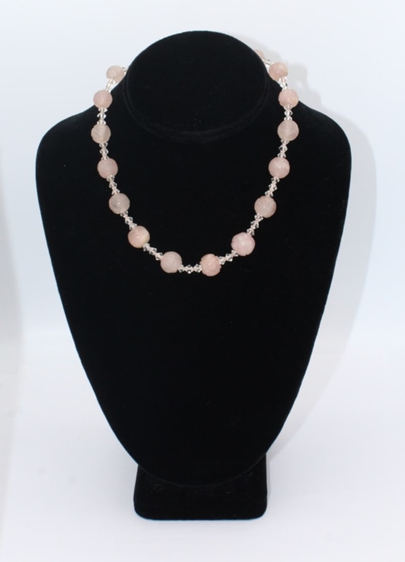 VINTAGE CARVED ROSE QUARTZ NECKLACE: NECKLACE WITH 17 LIGHT PINK ROSE QUARTZ CARVED BEADS SEPARATED WITH CLEAR BEADS. 16" LONG. ESTIMATE: $25-$50