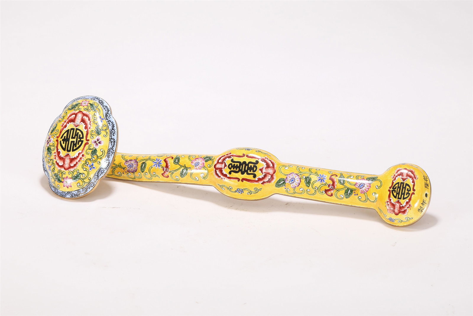 A PAINTED ENAMEL RUYI SCEPTER: A PAINTED ENAMEL RUYI SCEPTER The shaft with a central cartouche and a large quatrefoil head, fully decorated with auspicious pattern and floral scrolls, all against a yellow ground, a Qianlong four c