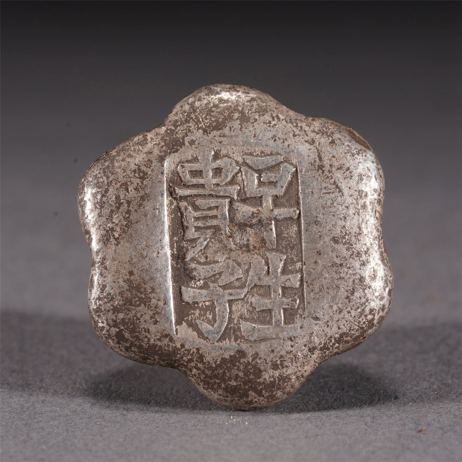 AN INSCRIBED SILVER INGOT: AN INSCRIBED SILVER INGOT Silver ingot in hexagonal shape, with inscription at the top. Dimension: 2x2x1 cm. Weight 38 gram.
