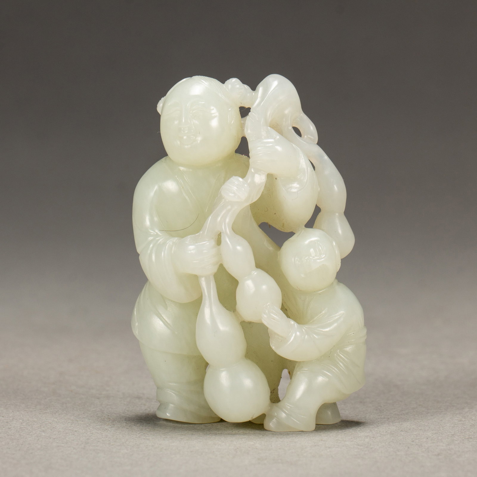 A CHINESE WHITE JADE CARVING: A CHINESE WHITE JADE CARVING The stone is carved and pierced depicting a boy holding a spray of double gourds over his back, alongside a smaller boy grasping a stalk of double gourds in his hands. The