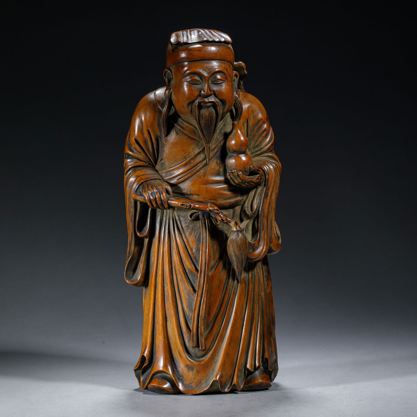 A CARVED BOXWOOD GOD OF LONGEVITY: A CARVED BOXWOOD GOD OF LONGEVITY The immortal carved in realistic form, wear long loosing robe, holding a double gourds in his left hand, and a horsetail whisk in his right hand. Dimension: L. 9 cm.