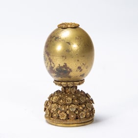 A BRONZE-GILT HAT FINIAL