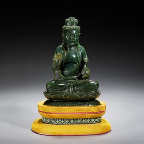 A CARVED SPINACH GREEN JADE SEATED GUANYIN