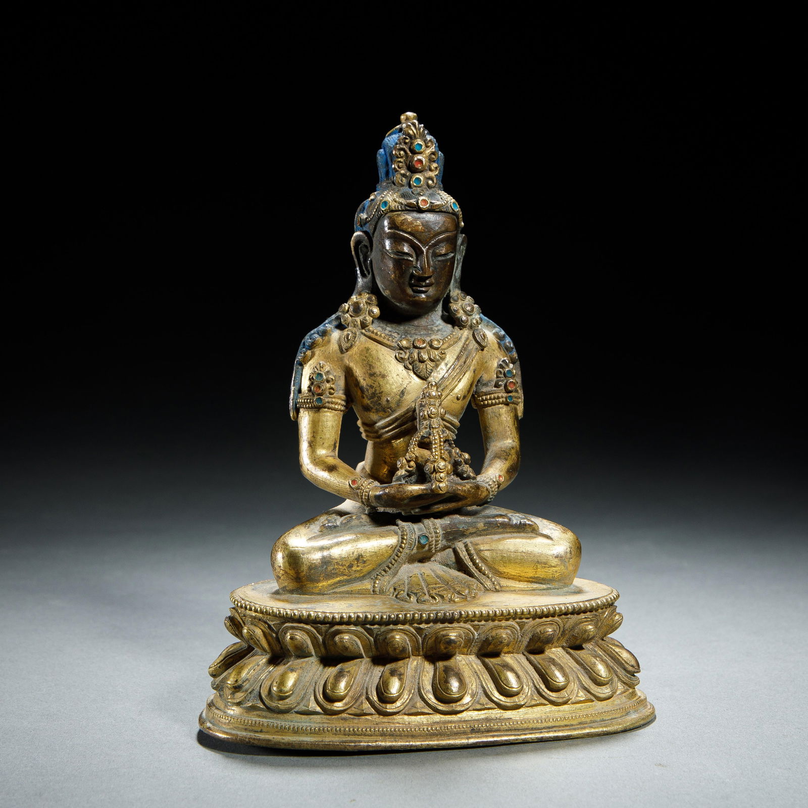 A BRONZE-GILT SEATED AMITAYUS: A BRONZE-GILT SEATED AMITAYUS This present lot portrays Amitayus, the bliss-body of the tathagata Amitabha. In Tibet, Amitayus is worshiped in a special ceremony for obtaining long life and is
