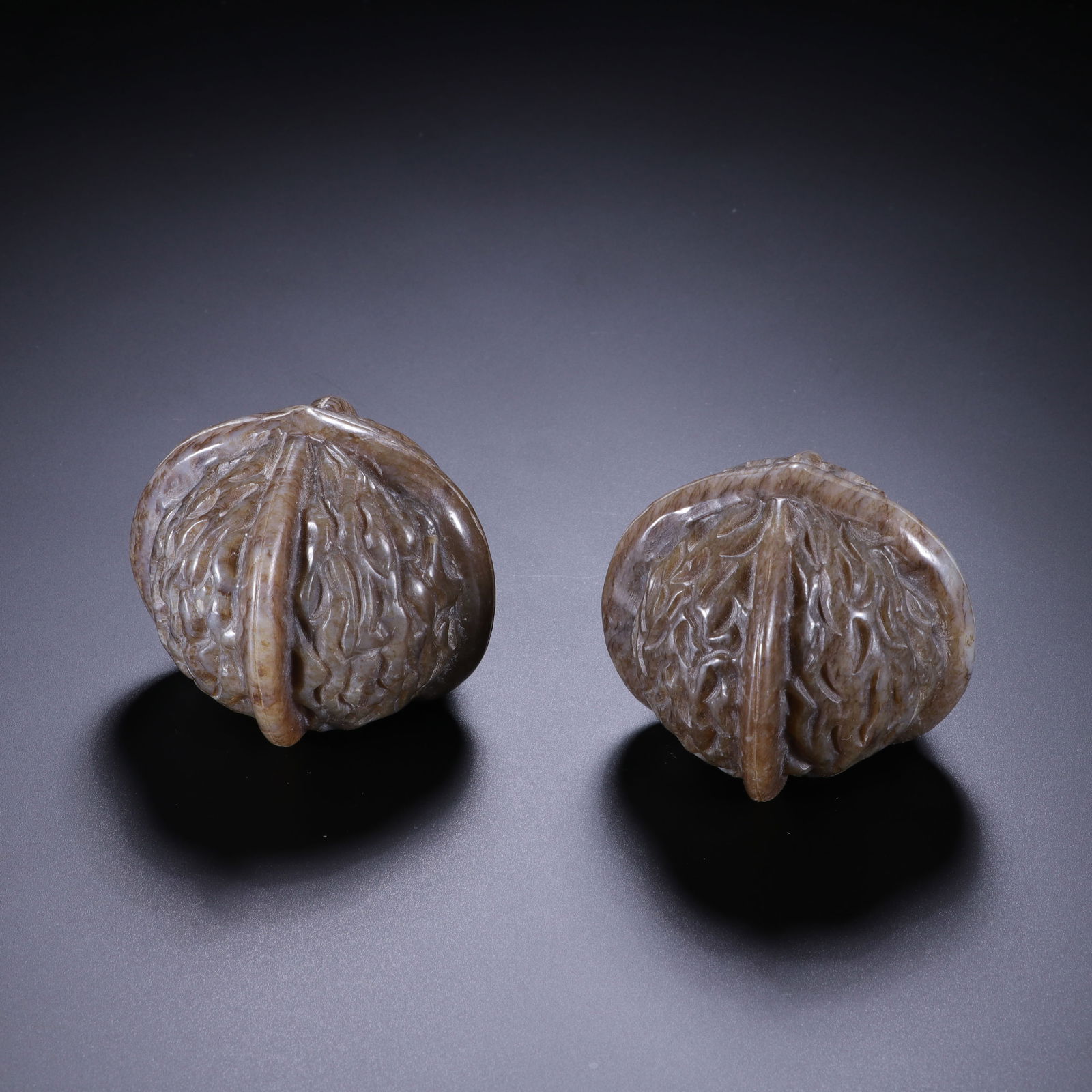 PAIR CARVED JADE CHESSNUTS: PAIR CARVED JADE CHESSNUTS Realistically carved in natural chestnut form, the stone is of brown tone. Dimension: H. 4.7 cm. cm. W. 5.6 cm. grams.