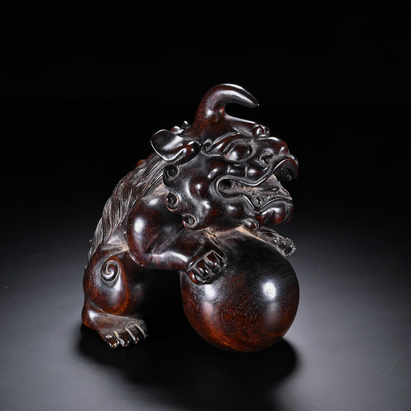 Chinese Zitan Wood 'Lion with Ball' Ornament: Chinese Zitan Wood 'Lion with Ball' Ornament This finely carved zitan wood ornament measures 13 cm in height and 11.5 cm in width. The rich, lustrous dark wood depicts a mythical lion (or qilin-like b