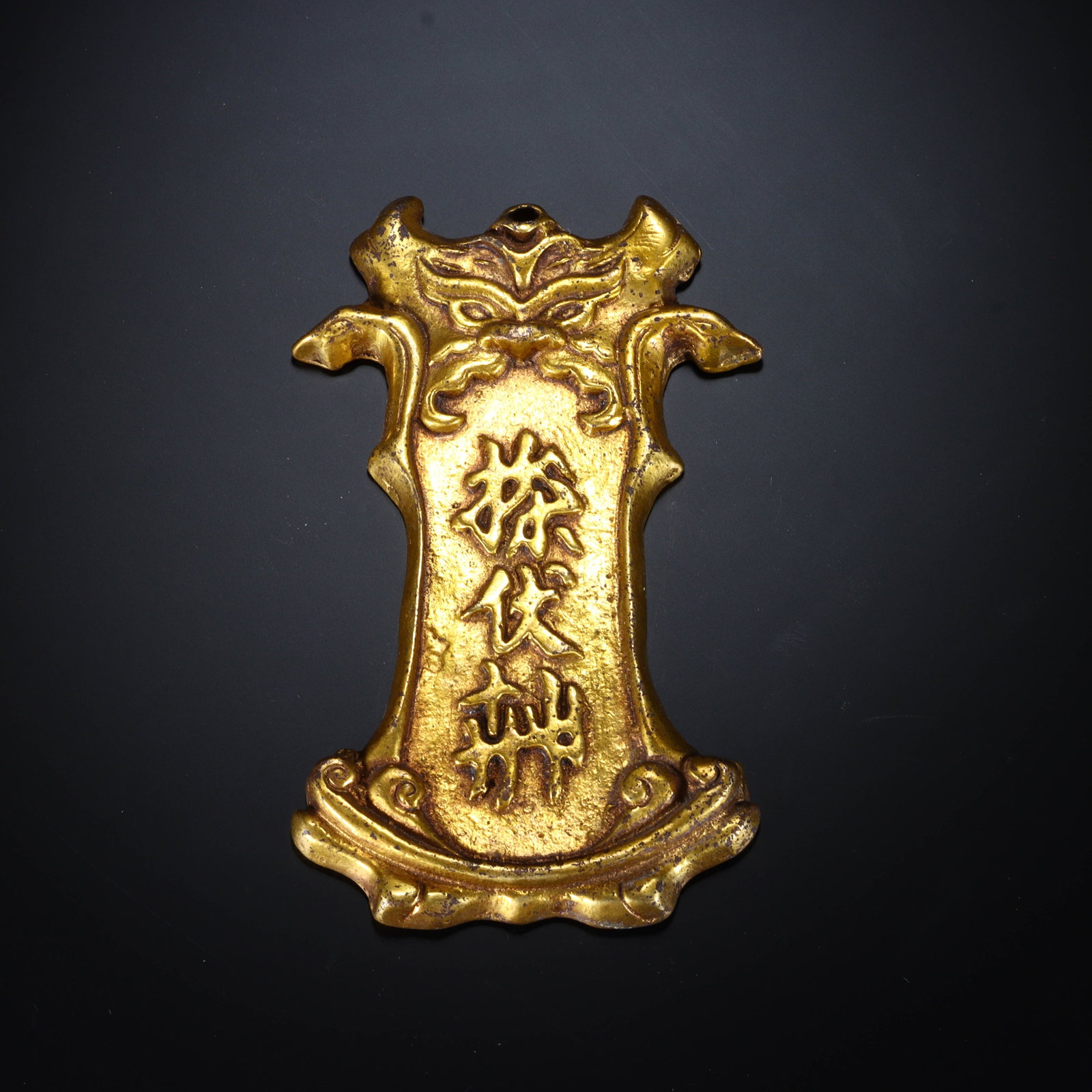 Chinese Gilt Bronze Tablet with Mythical Beast and Characters: Chinese Gilt Bronze Tablet with Mythical Beast and Characters This finely cast gilt bronze tablet measures 11.4 cm in length and 6.5 cm in width. The plaque features an ornate, axe-shaped form with a 