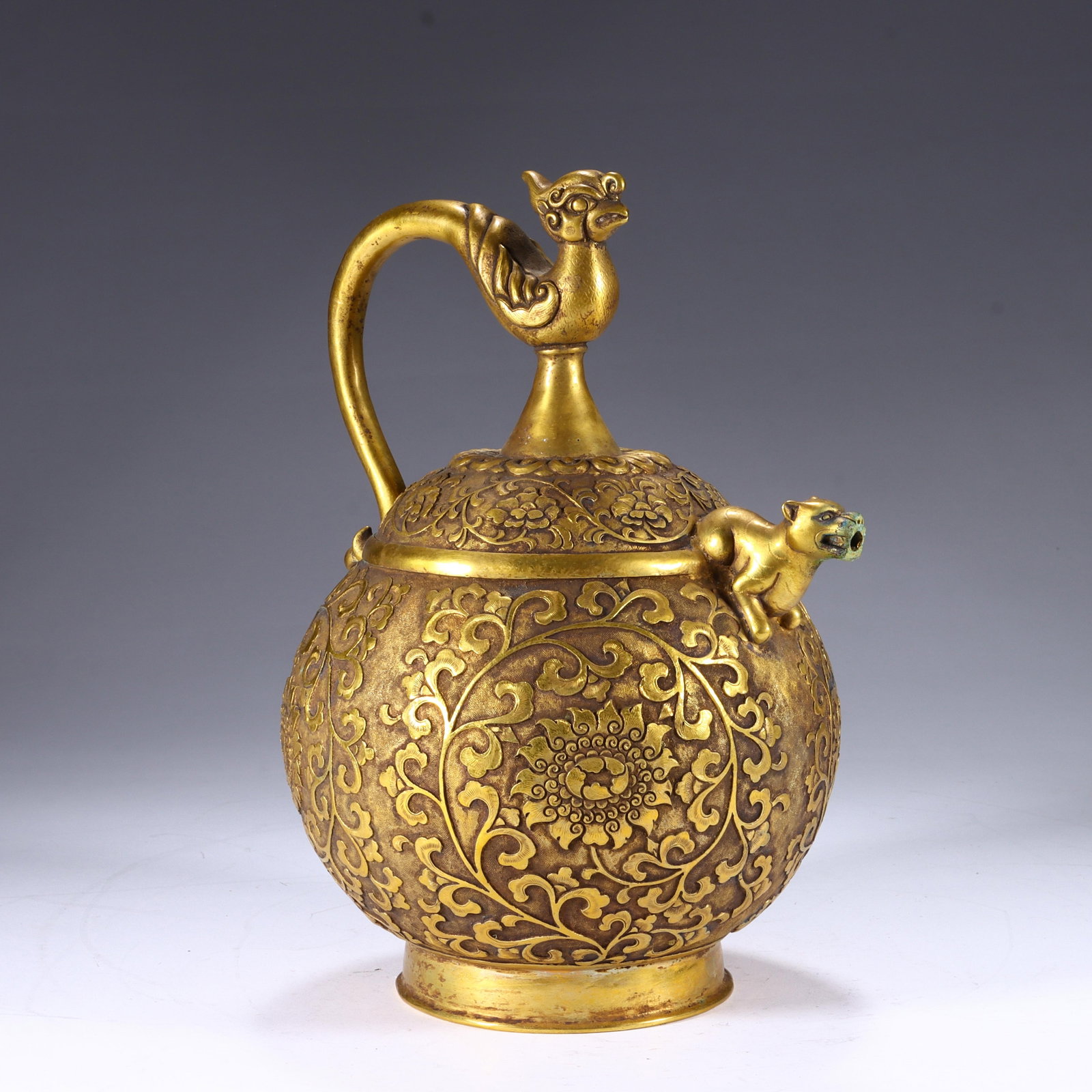 Chinese Gilt Bronze Phoenix-Handled Ewer with Beast Spout: Chinese Gilt Bronze Phoenix-Handled Ewer with Beast Spout This finely crafted gilt bronze ewer measures 21.5 cm in height and 17 cm in width. The rounded body is richly adorned with repousse floral