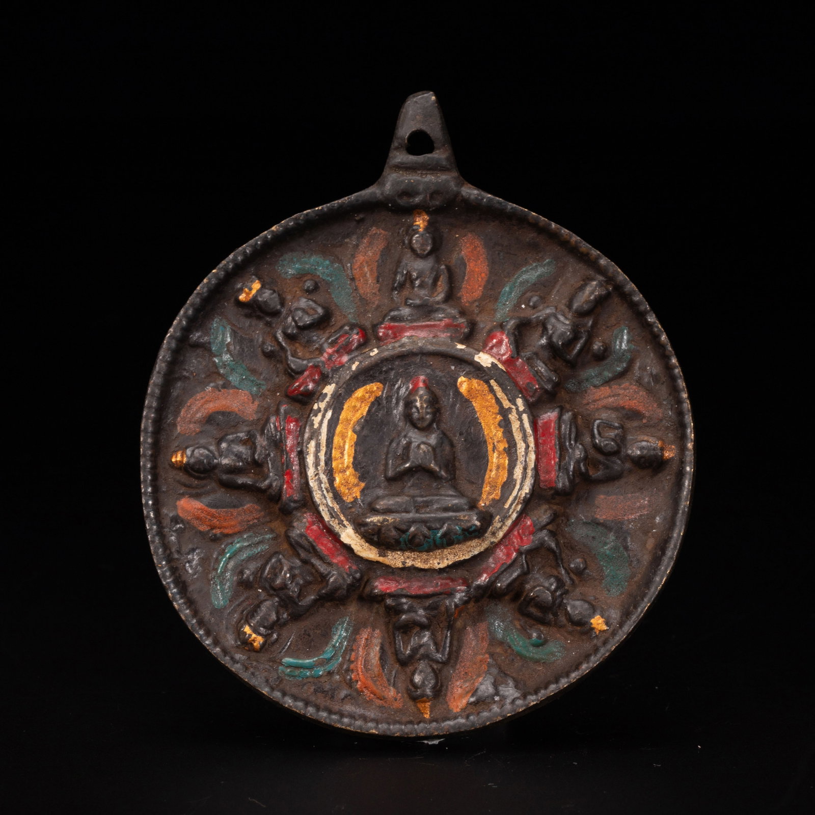 Chinese Tibetan Painted Bronze Amulet Pendant: Chinese Tibetan Painted Bronze Amulet Pendant A circular Tibetan bronze amulet pendant with polychrome painted details, featuring a central seated Buddha surrounded by eight additional figures arrange