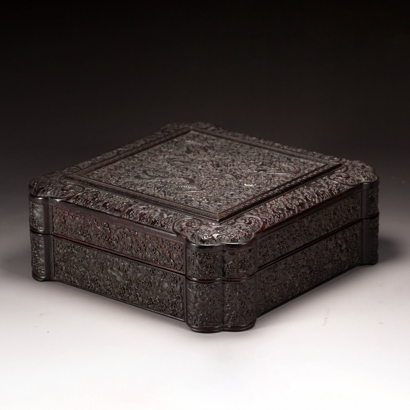 Chinese Zitan Wood Dragon-Carved Square Box: Chinese Zitan Wood Dragon-Carved Square Box A square box meticulously crafted from dense zitan wood, featuring deeply carved relief decoration across all surfaces. The lid's central panel depicts a dy