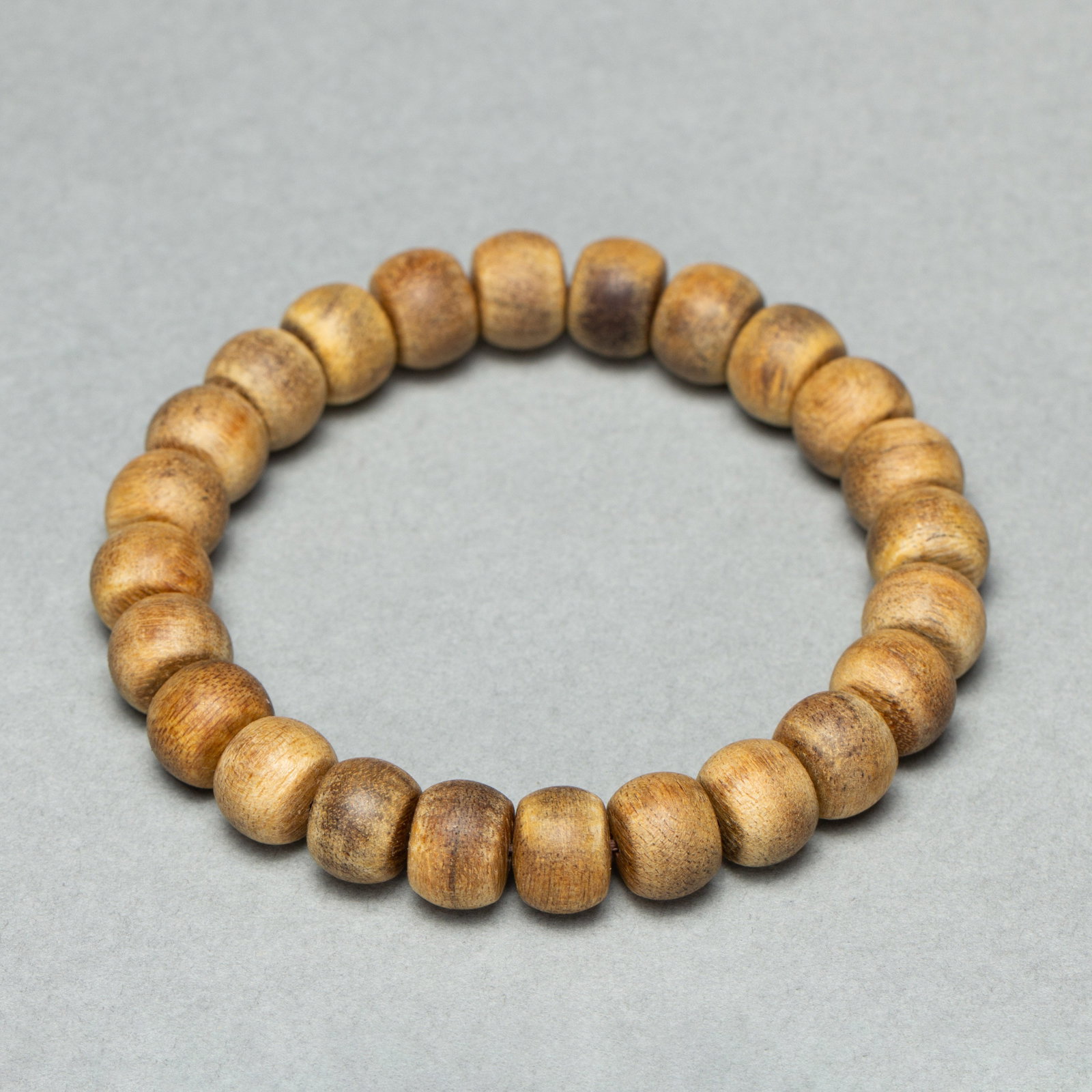 Chinese Agarwood Beaded Bracelet: Chinese Agarwood Beaded Bracelet A single strand bracelet crafted from smooth barrel-shaped agarwood beads, each with a natural light brown hue and visible wood grain patterns. The beads are uniformly