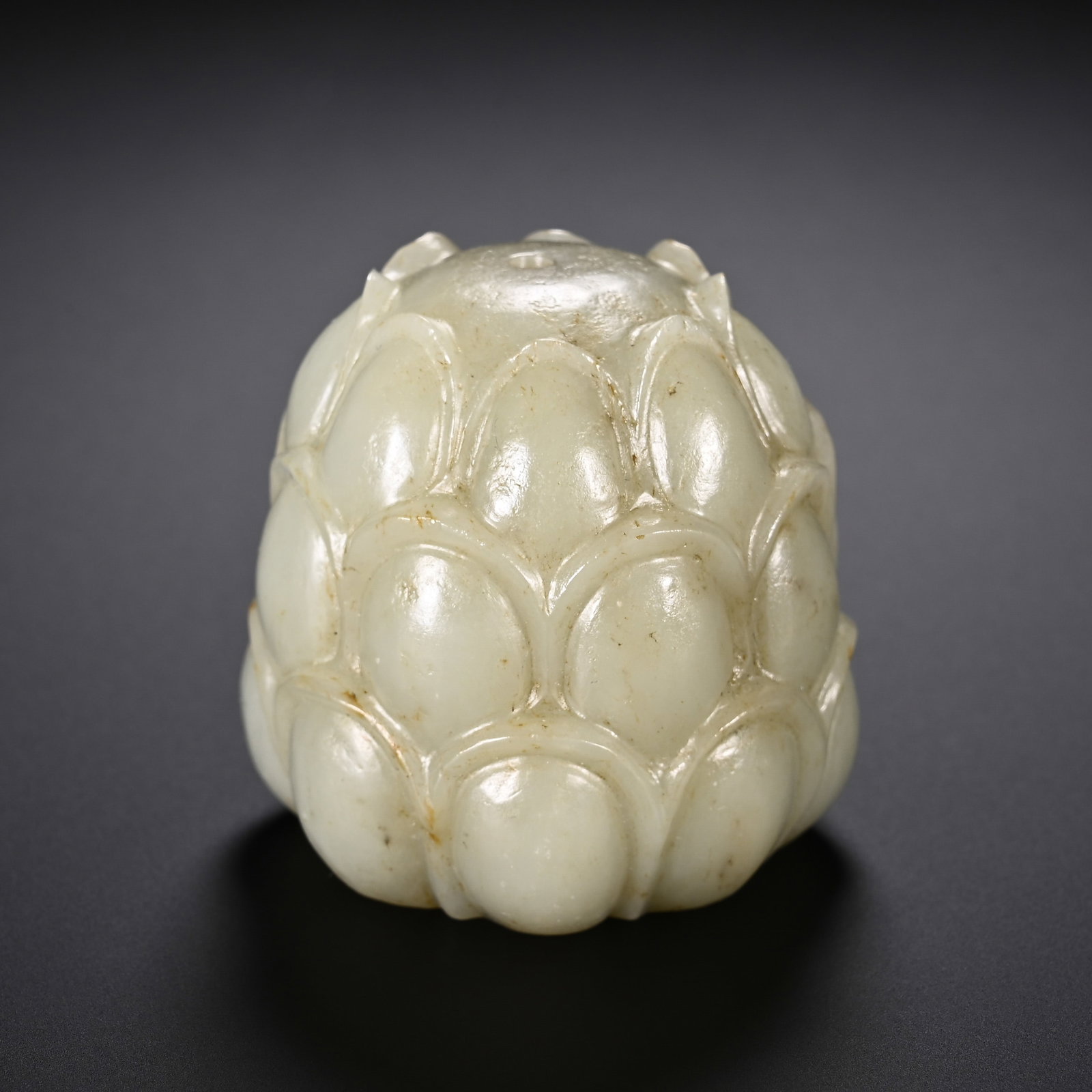 A Chinese Hetian Jade Lotus Incense Holder: A Chinese Hetian Jade Lotus Incense Holder A Chinese Hetian jade incense holder carved in the form of a closed lotus bud. The stone is rendered with overlapping, smooth petals, and a small aperture at