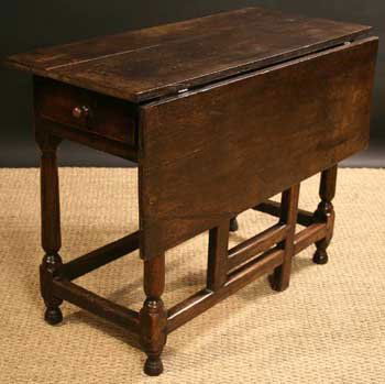 A Late 17th/Early 18th Century Joined Oak Drop-lea: A Late 17th/Early 18th Century Joined Oak Drop-leaf Table. The rectangular top measuring 38½ ins x 29 ins (98 cms x 74 cms) with a single drop leaf on a swing-out gate and a drawer at one end. Standi