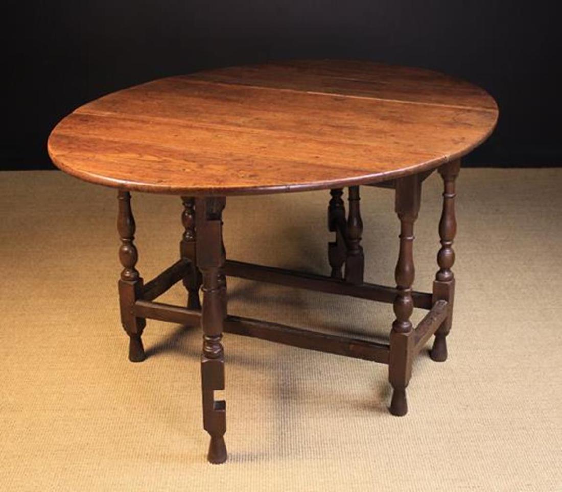 A Joined Oak Gateleg Dining Table. The oval drop leaf: A Joined Oak Gateleg Dining Table. The oval drop leaf top on baluster legs with ball & reel turnings, united by peripheral stretchers and raised on turned feet, 28¾ in (73 cm) high, 43 in x 56 in (11