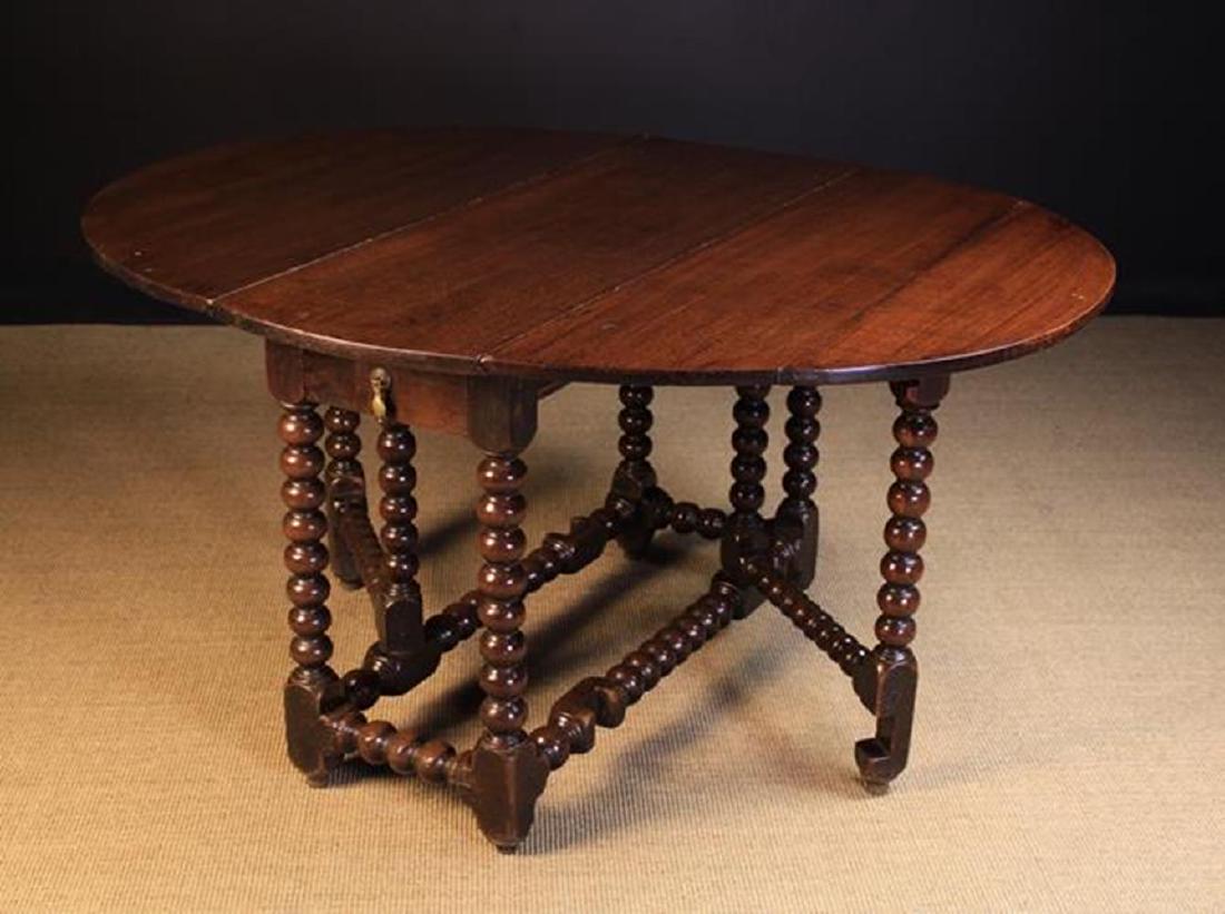 A 17th Century Oak Gate-leg Dining Table Circa 1680.: A 17th Century Oak Gate-leg Dining Table Circa 1680. The oval drop leaf top on graduated ball turned legs and gates united by conforming stretchers with a frieze drawer to one end, 29 in (74 cm) high,
