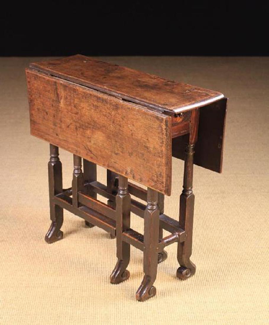 A Small Late 17th Century Oak Gateleg Table. The: A Small Late 17th Century Oak Gateleg Table. The rectangular top having two drop leaves supported by turned legs and gates with carved braganza feet. One end fitted with a drawer, 28'' (71 cm) high, 3
