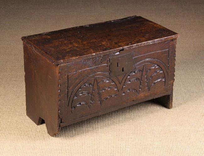 A 17th Century Child's Boarded Oak Coffer (A/F). T: A 17th Century Child's Boarded Oak Coffer (A/F). The plank front gouge carved with lunettes and having chip carved ends, standing on end boards 38 cm high, 60 cm wide, 34 cm deep (15'' h. 23¾''