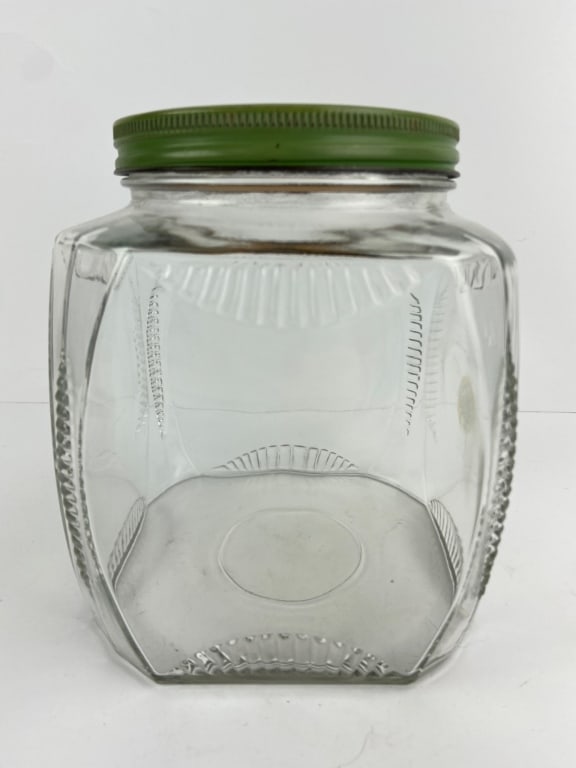 Antique Art Deco Hoosier Cabinet Glass Jar: Clear glass jar with geometric Art Deco design, featuring a green metal lid. Originally intended for Hoosier cabinets. Shows minor wear consistent with age.