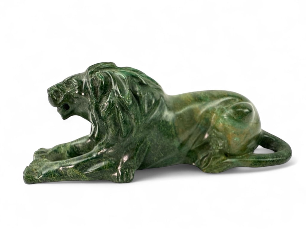 Green Carved Jade African " Lion Figurine: A green carved Jade or Jade like stone lion figurine measuring approximately 5.25 inches in length and 2 inches in height. Features intricate carved details and a natural stone finish. Unknown maker.