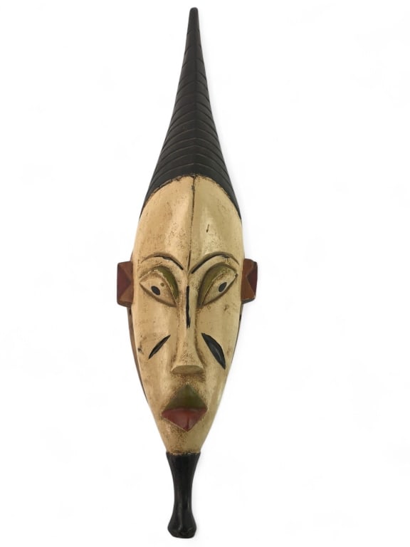 Vtg Wood Carved African Mask: Vintage wood carved African mask measuring 23 inches. Features a tall, pointed headdress and hand-painted details in earthy tones. Visible wear on the reverse side, showcasing the natural aged look of