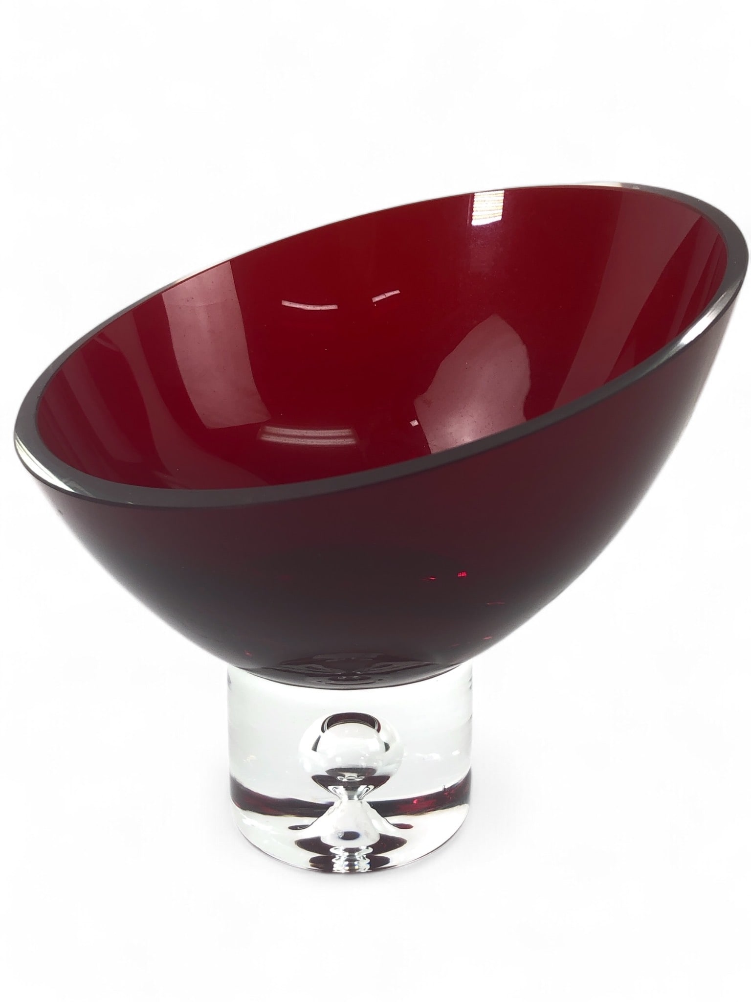 Red Glass Bowl With Clear Pedestal Base: A red glass bowl standing 5.5" tall with a clear pedestal base featuring a bubble design element. The bowl has a smooth finish, with minor wear visible along the rim. Elegant and striking in design.