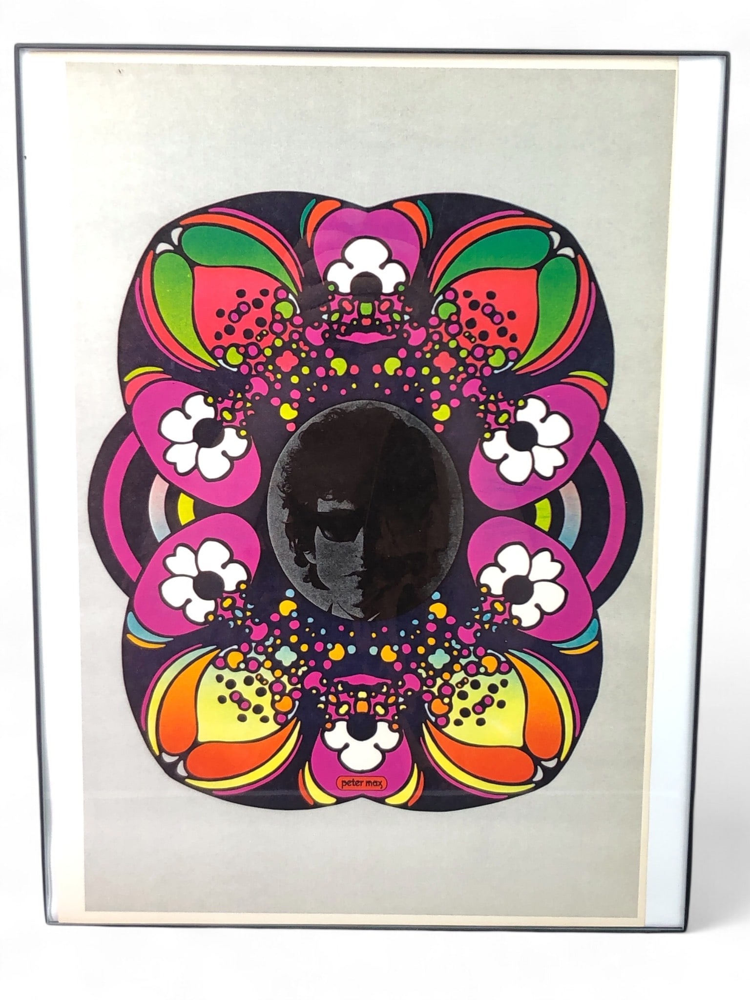 1970 Peter Max Bob Dylan Poster Framed: 1970 Peter Max-designed "Bob Dylan" poster featuring vibrant colors and floral motifs, framed in a minimalist black frame. Measures 12" x 16". Ready for wall display.