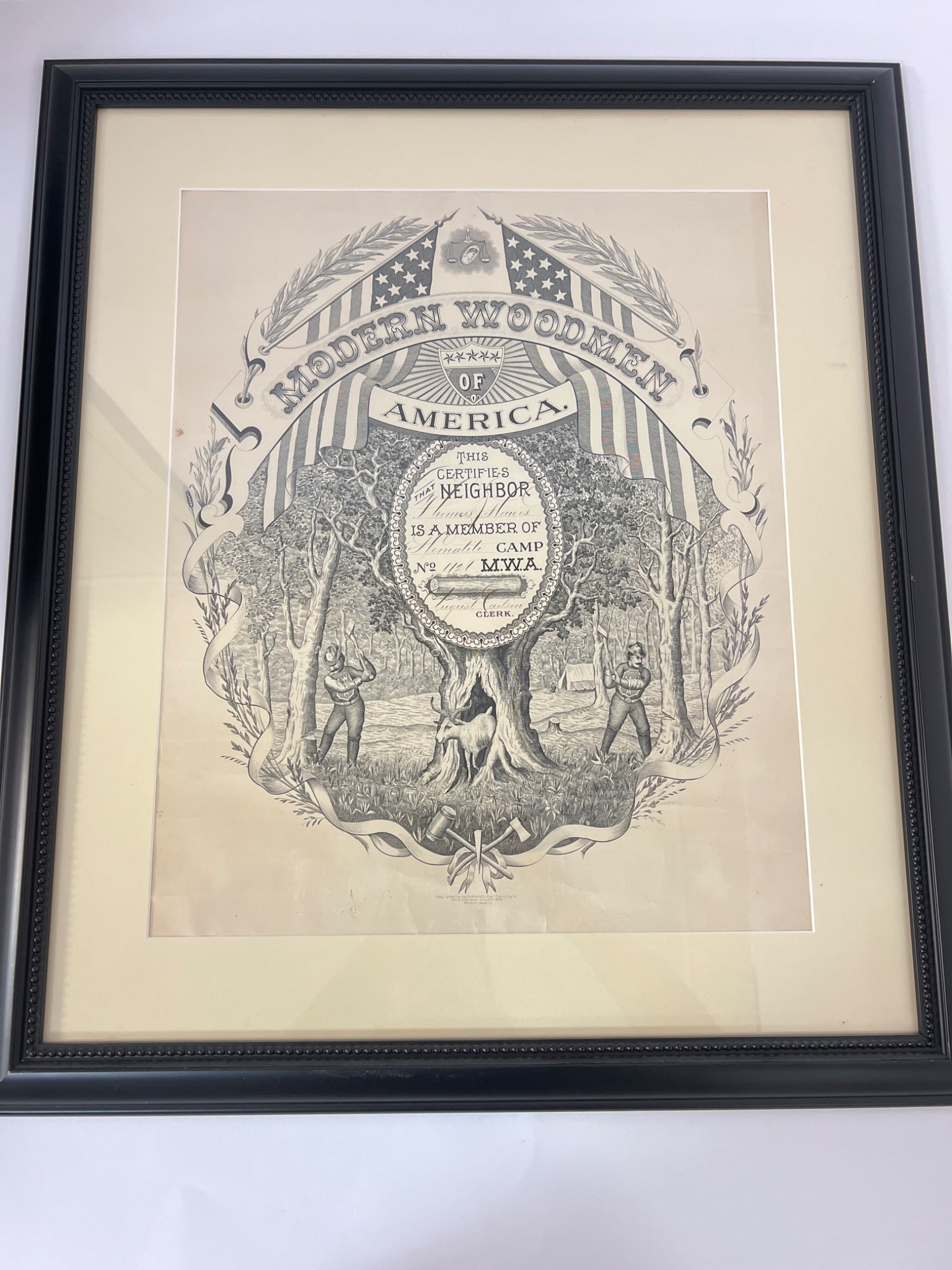 1889 Modern Woodmen of America Certificate: Framed print of a certificate from the Modern Woodmen of America, dated July 10, 1899. Measures 23.5"x 27"and features intricate woodcut-style imagery. Frame by Frames Unlimited. L3