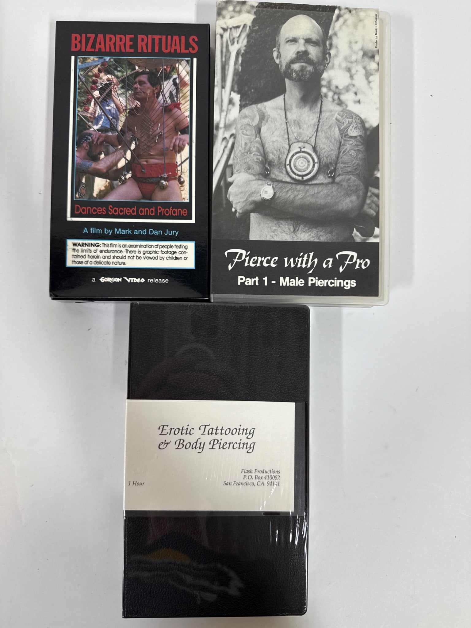 Tattoo And Piercing VHS Tapes: Three VHS tapes: 'Bizarre Rituals: Dances Sacred and Profane', 'Pierce With a Pro: Part 1 - Male Piercings', and 'Erotic Tattooing & Body Piercing', which is sealed.