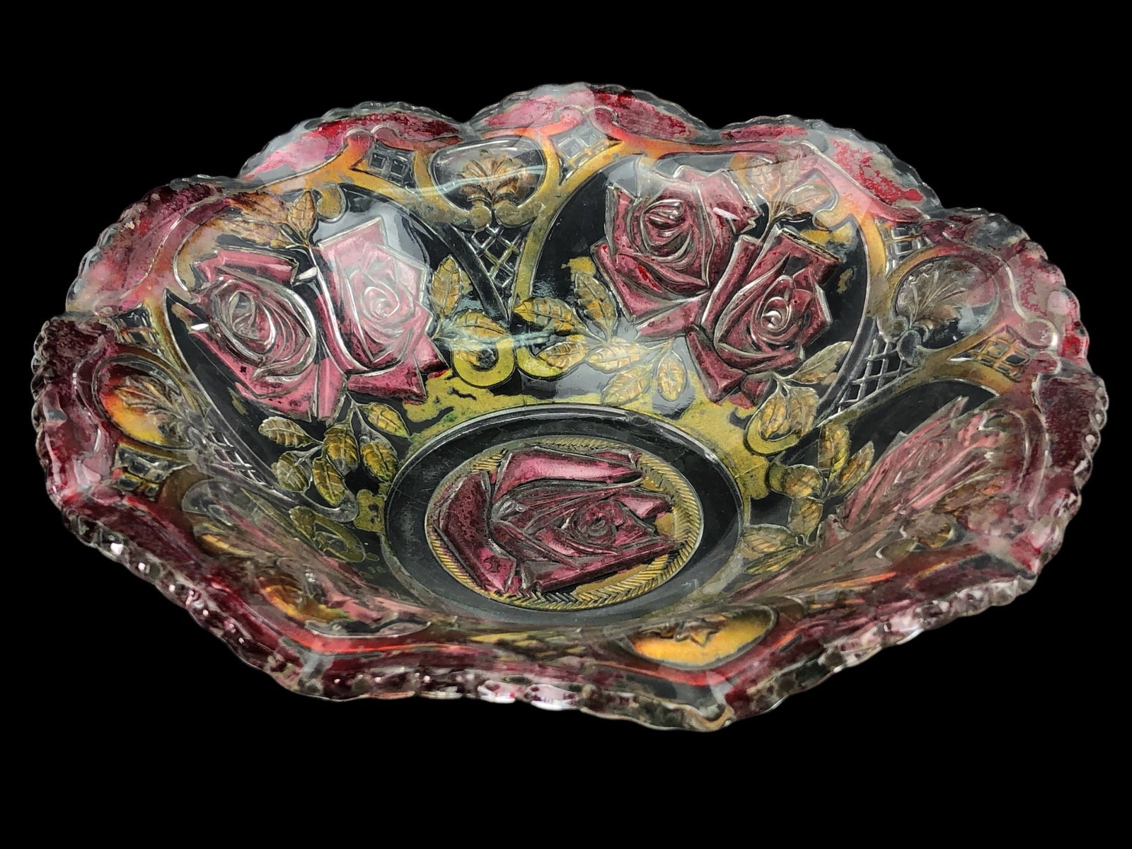 A Goofus Glass Bowl with Red and Gold Rose Design: A Goofus Glass bowl, of scalloped, pressed glass construction. The decorative bowl features a robustly molded floral design dominated by roses and foliage. The vibrant decoration, appearing to be reve