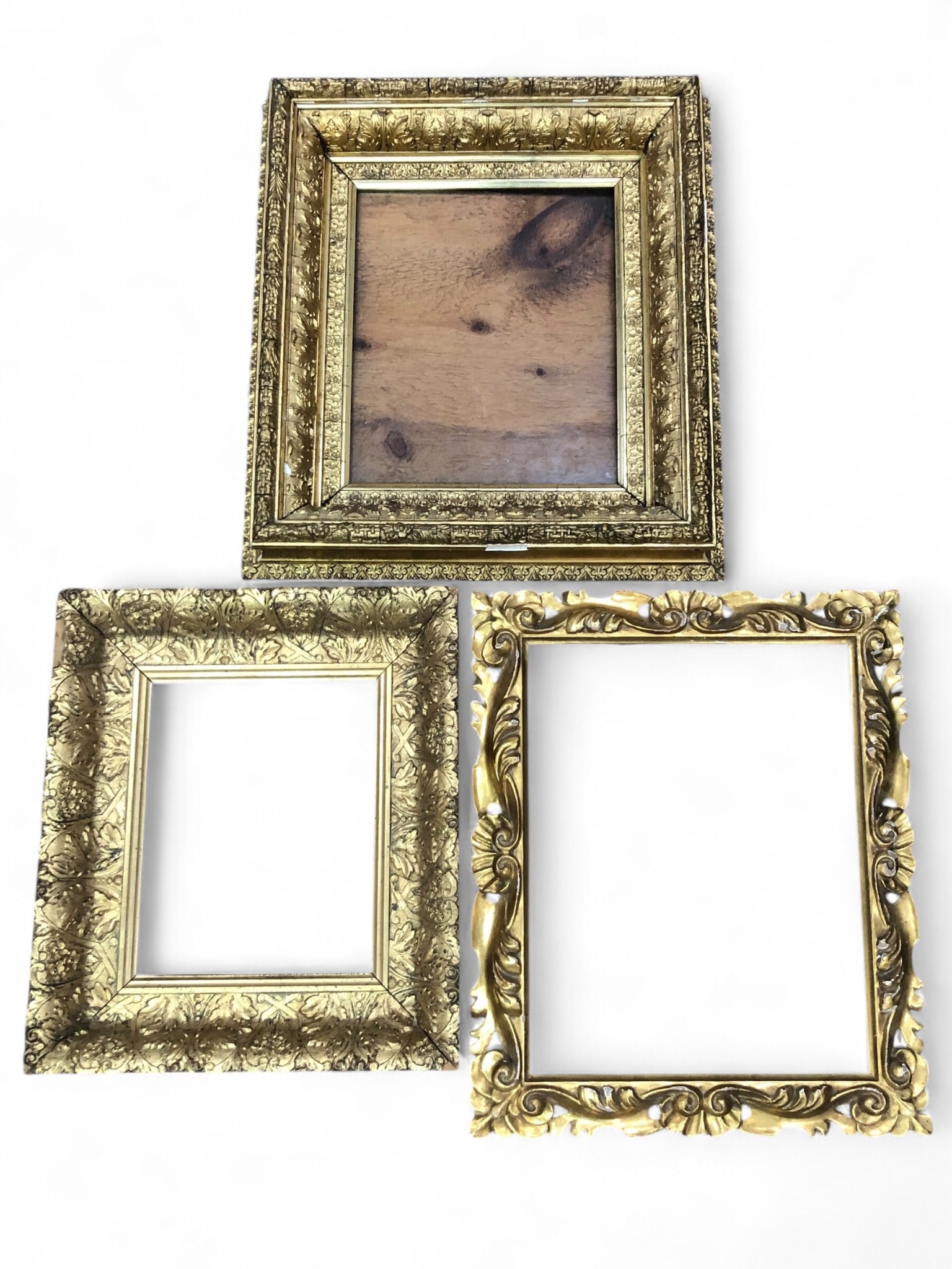Three Ornate Giltwood and Composition Picture Frames: Three gold ornate wooden frames in varying sizes. Dimensions are approximately 12 3/4 x 15 inches, 14.5 x 17.5 inches, and 16.5 x 18.5 inches. One frame includes glass. Detailed floral and scroll desi
