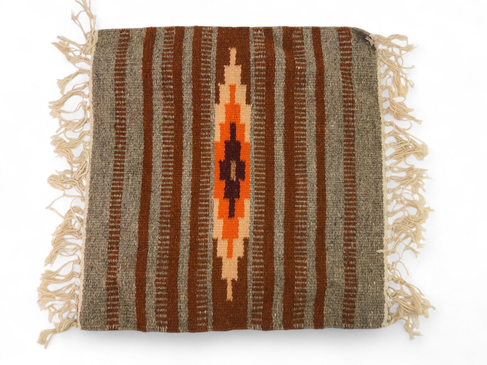 Vg Navajo Hand Woven Miniature Rug: Navajo hand woven miniature rug measuring 15 x 15.5 inches, excluding fringe. Features a central geometric pattern in warm orange, cream, and brown tones, surrounded by striped borders with fringe det