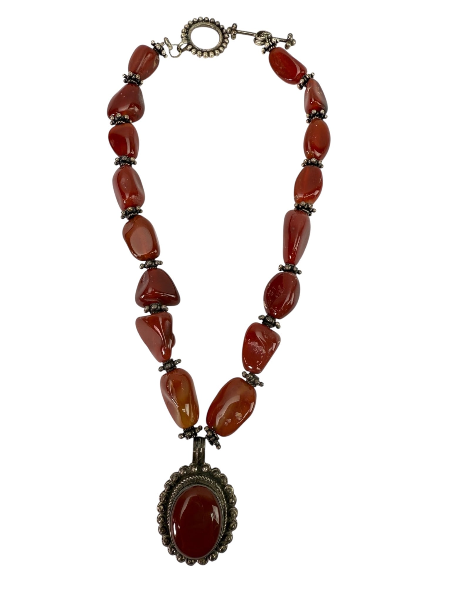 Sterling Carnelian Pendant Necklace 16?: 16-inch sterling silver necklace featuring a pendant stamped 925. The necklace is adorned with carnelian beads and an oval sterling silver pendant with a carnelian stone centerpiece. Toggle clasp clos