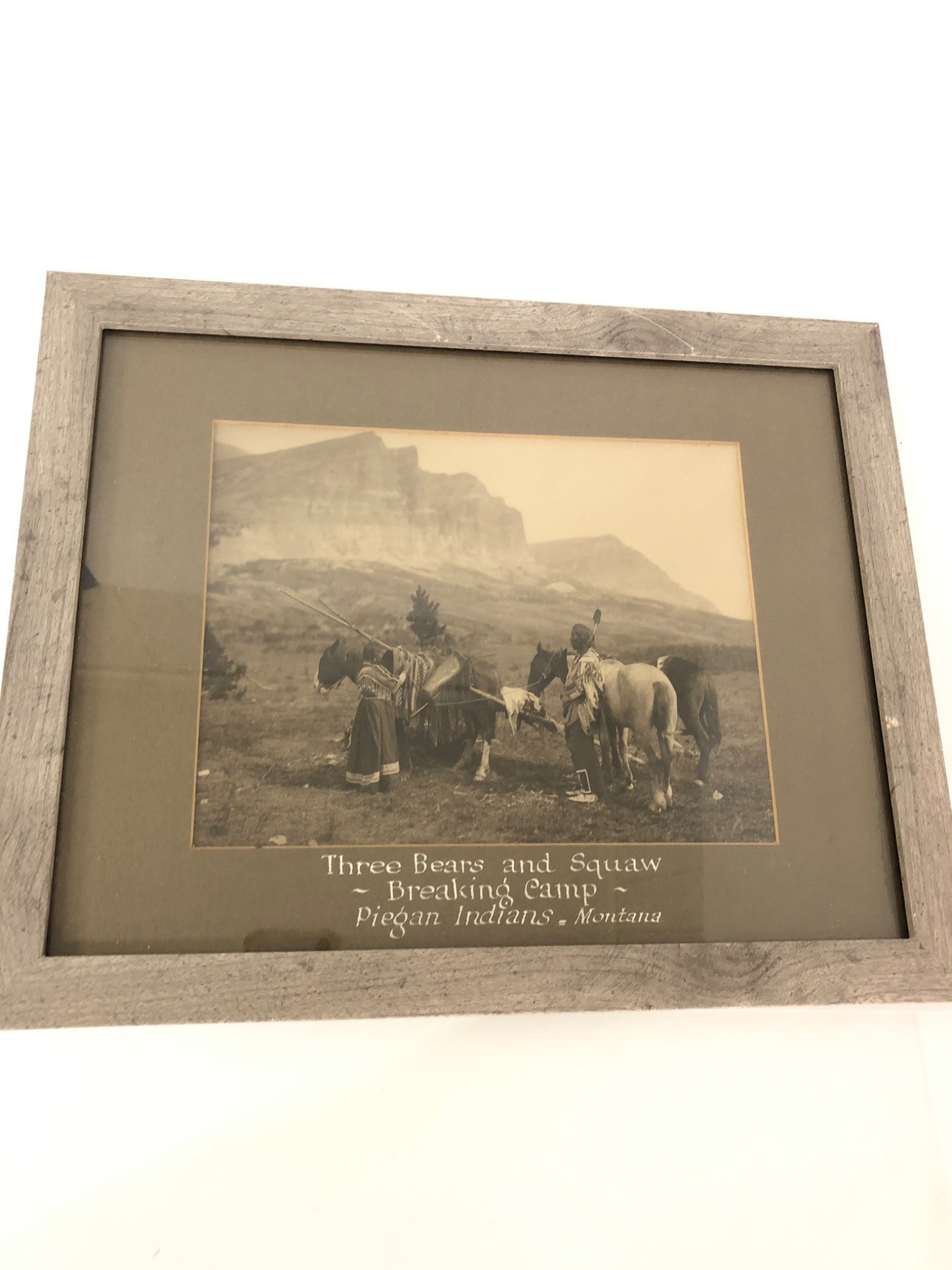 Three Bears And Squaw Breaking Camp Photo: Framed photograph titled ‘Three Bears and Squaw – Breaking Camp – Piegan Indians – Montana.’ The overall dimensions, including frame, measure 16? x 13?. Features a rustic-style wood frame an