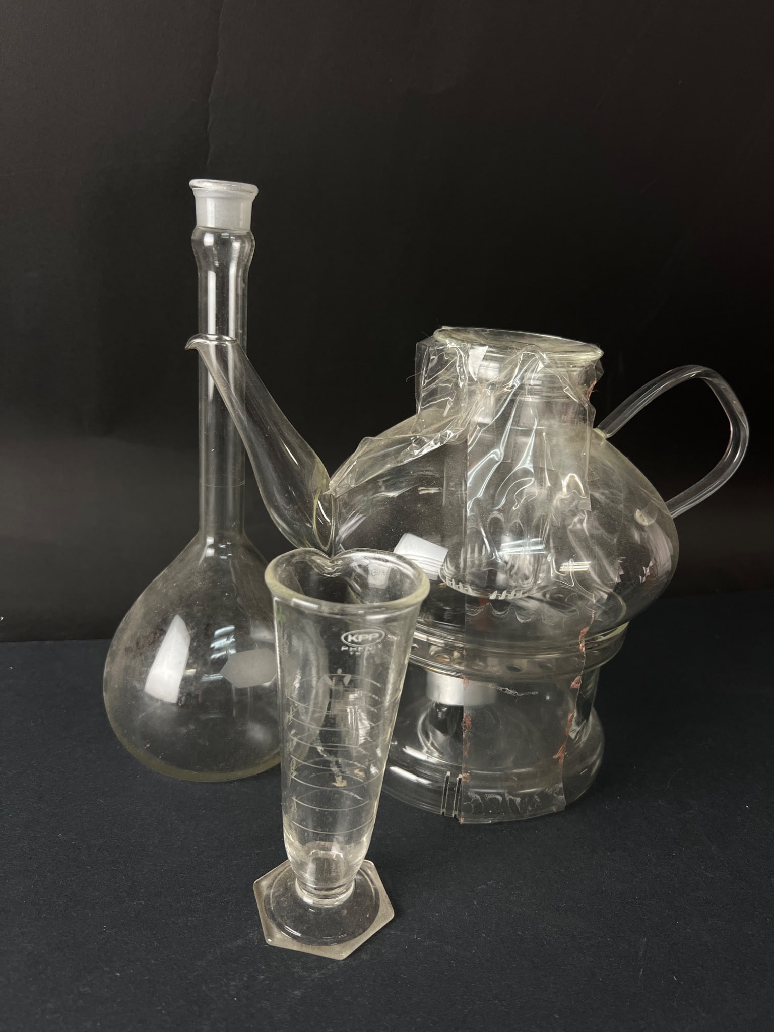 Schott Mainz Jena Glass Teapot With Beakers: A Schott Mainz ‘Jena Glass’ glass teapot with infuser and warmer, made in Germany. Includes vintage glass beakers, a Kimax USA 500ml round-bottom flask, and a tall graduated measuring glass marked