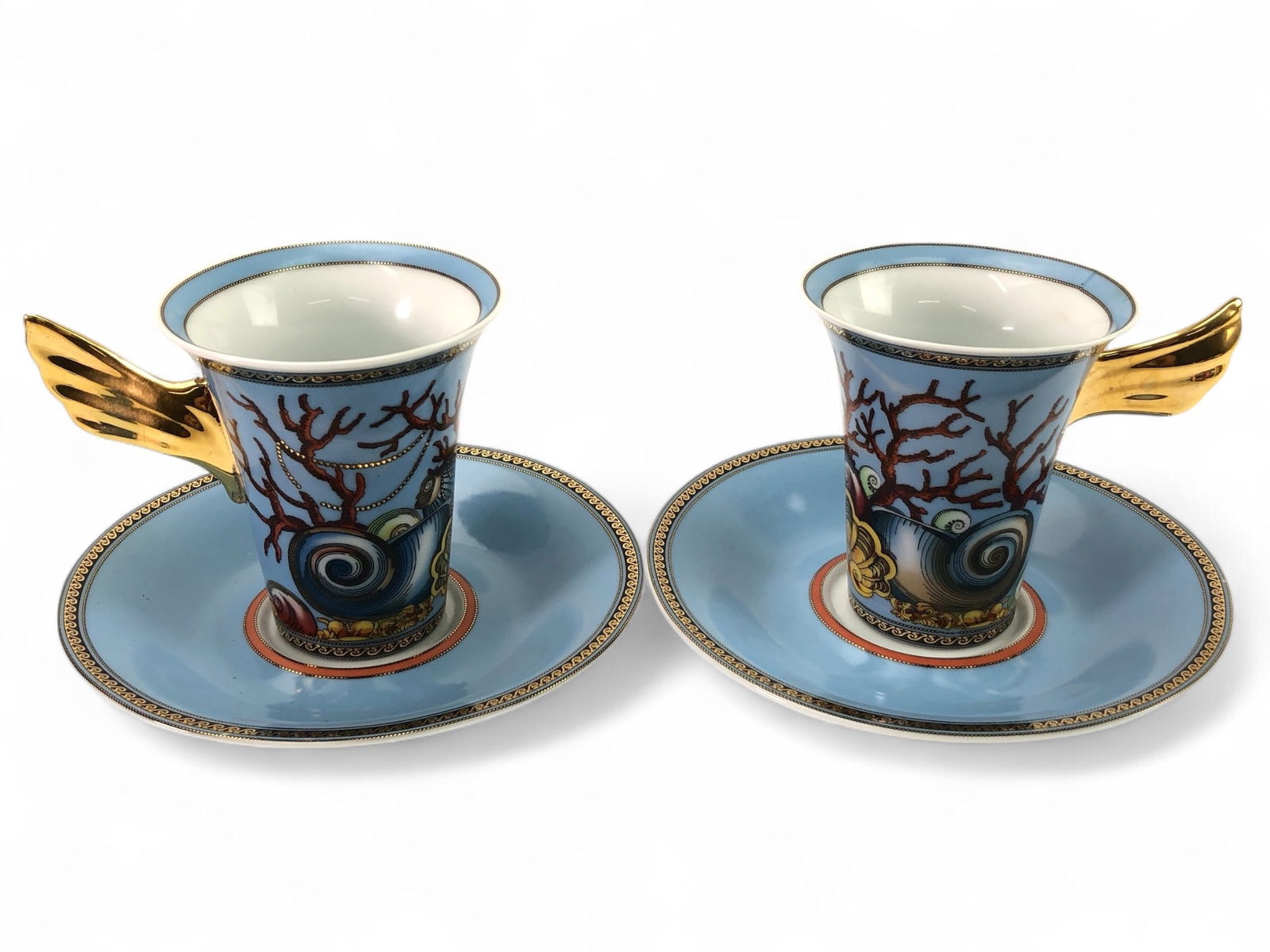 Rosenthal Versace Les Tresors De La Mer Set: Versace Les Tresors De La Mer cups with matching saucers. Vibrant ocean-inspired design featuring coral, shells, and gold-tone winged handles. Cups measure 3.5 inches tall, saucers 5 3/4 inches in dia