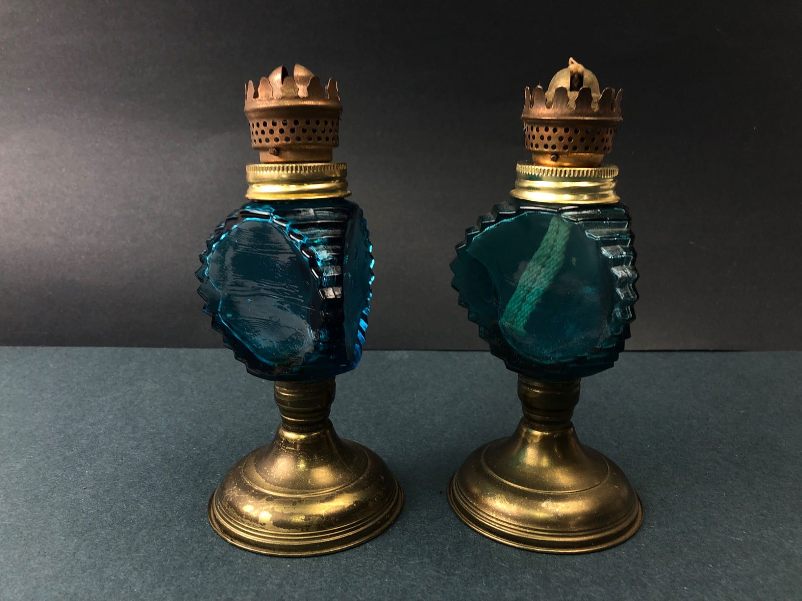 Antique Blue Glass & Brass Oil Lamps: Antique oil lamps featuring blue glass bodies with brass bases & burners. Each lamp stands approximately 7 inches tall. Shows wear consistent with age, including some tarnish on the brass. A decorativ
