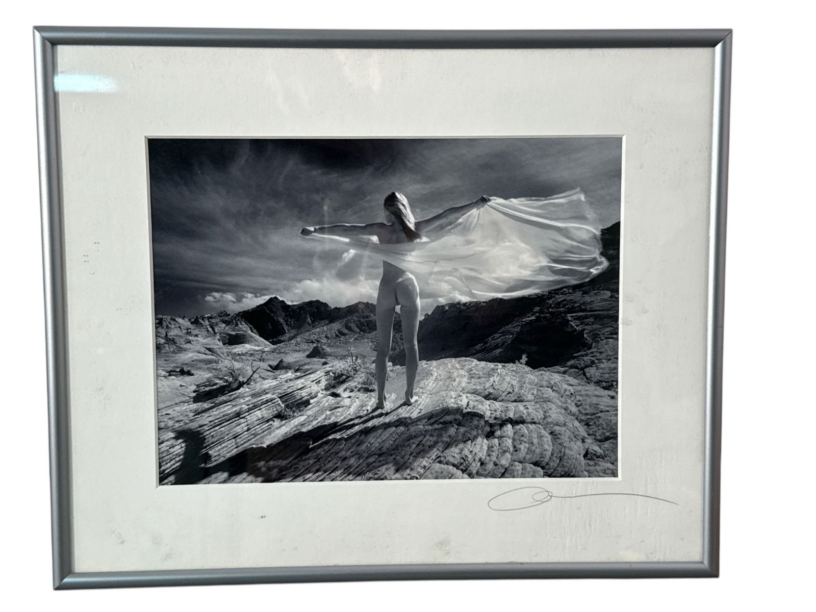 Framed Black & White Photograph In Desert: A framed black & white fine art photograph featuring a nude figure in a desert landscape. The frame measures 24x12 inches, and the artwork is signed. It includes a wire hanger on the reverse for wall