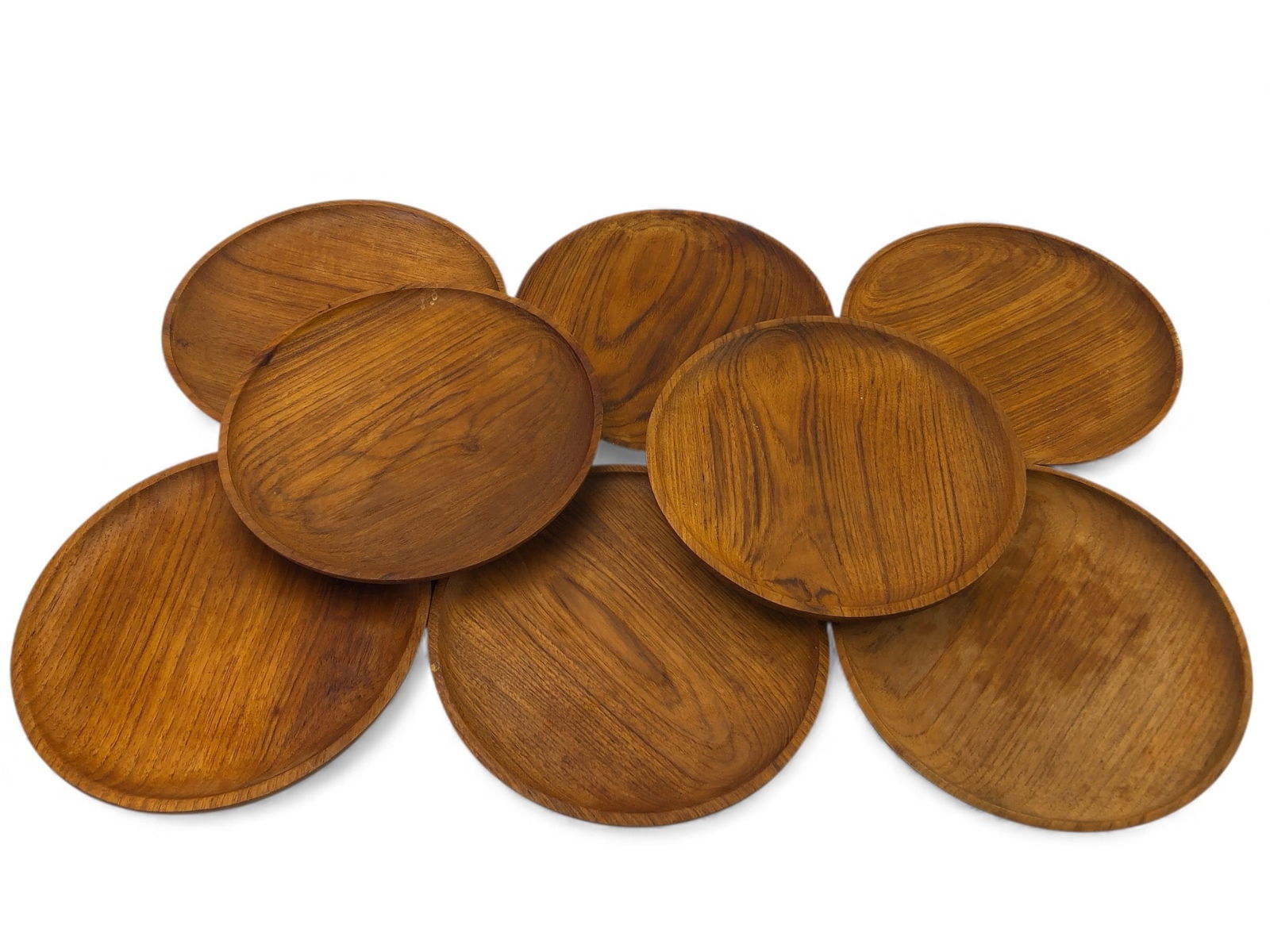 8 Teak Wood Plates Made In Thailand: Eight round teak wood plates with a 9.5-inch diameter, made in Thailand. Featuring a smooth finish with visible wood grain. Suitable for various uses and showing slight wear consistent with material.