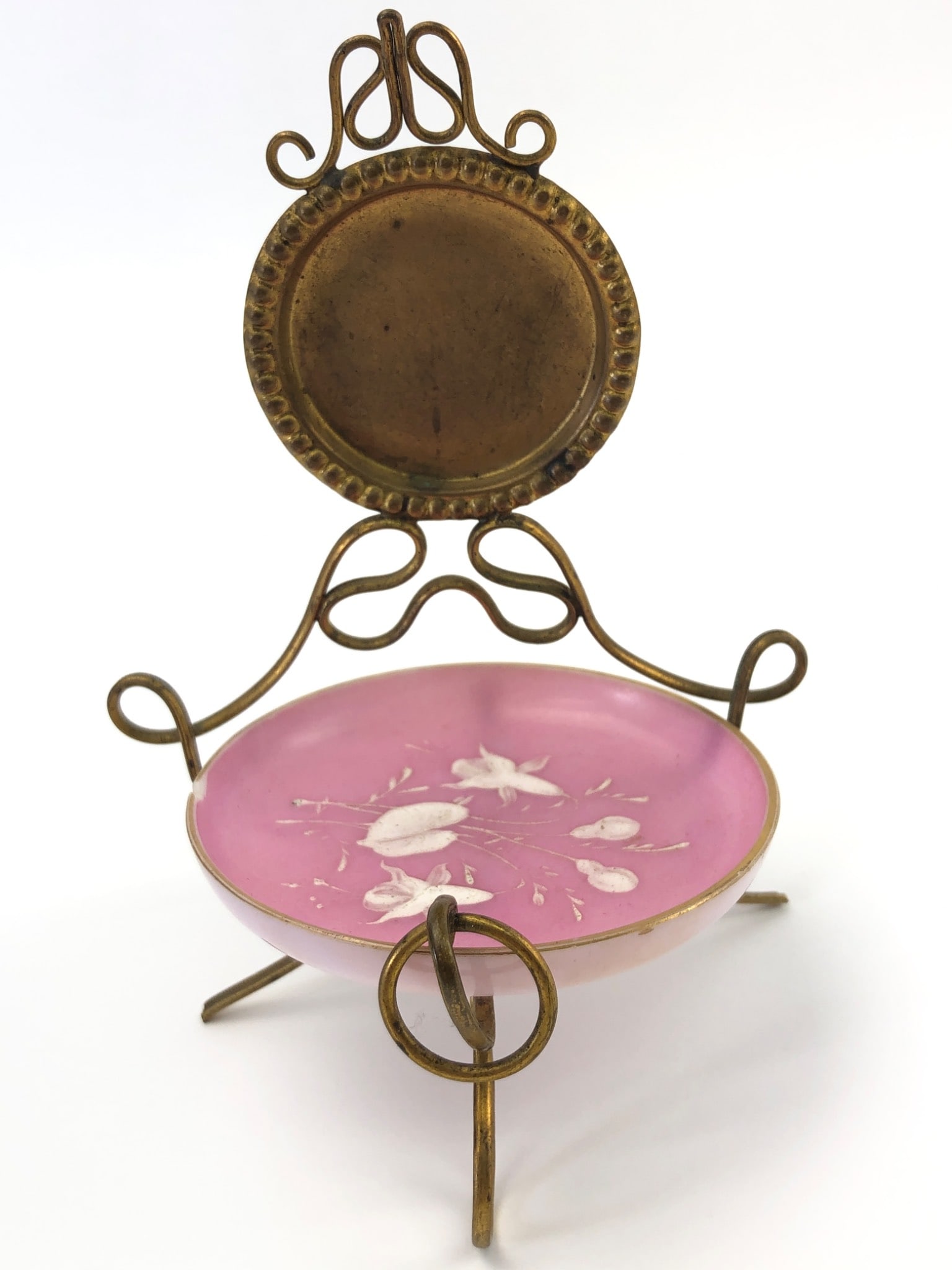 Vanity Miniature Trinket Dish With Stand: Vanity miniature trinket dish with stand, approximately 6 inches tall. Features a pink dish adorned with white floral design, gold trim, and a decorative brass/metal tin frame. Notable chip on the dis