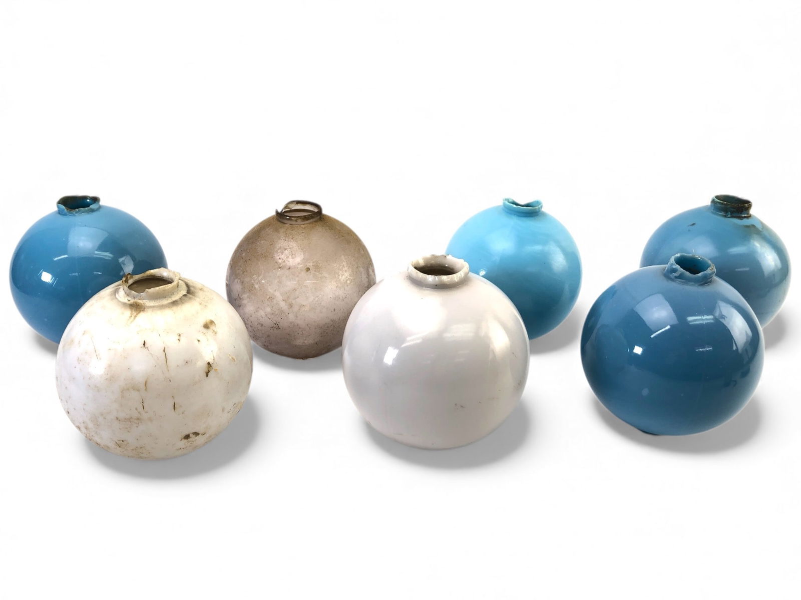 7 Glass Lightning Rod Balls With Holes: 7 glass lightning rod balls with holes at either end. Multiple colors including 4 blue, 2 white, & 1 clear. Rim edges are chipped, and the items require cleaning. Each ball is approximately 5 to 5.25