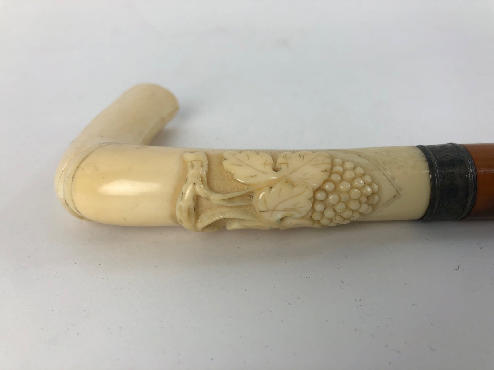 Carved Bone & Sterling Cane: Cane measuring 35 inches featuring a detailed carved handle, Possibly bone and a metal band with an engraved name on possibly sterling silver band. Notable wear present on the item and a visible crack