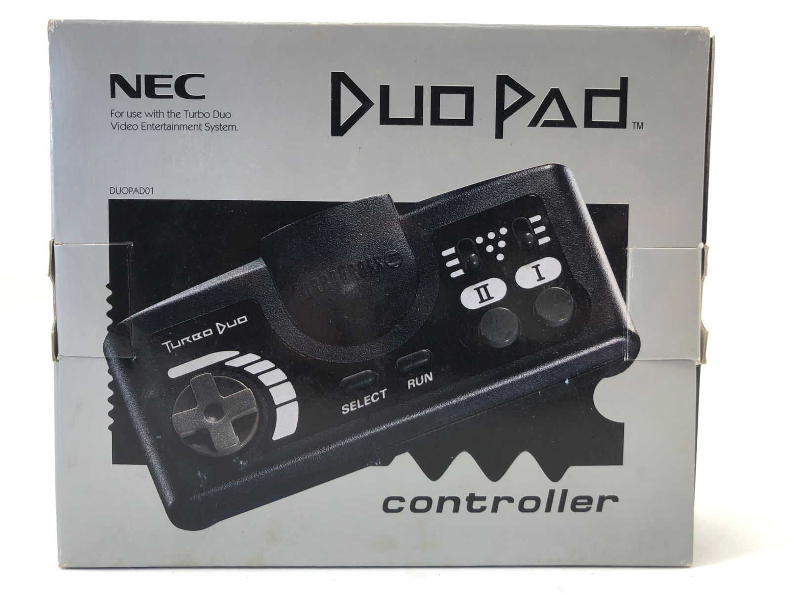 Nec Duo Pad Controller With Box: NEC Duo Pad controller with original box. Includes Turbo Duo controller with cord and original clear plastic packaging. Box shows minor wear and tear, with scuffs on edges. Controller features directi
