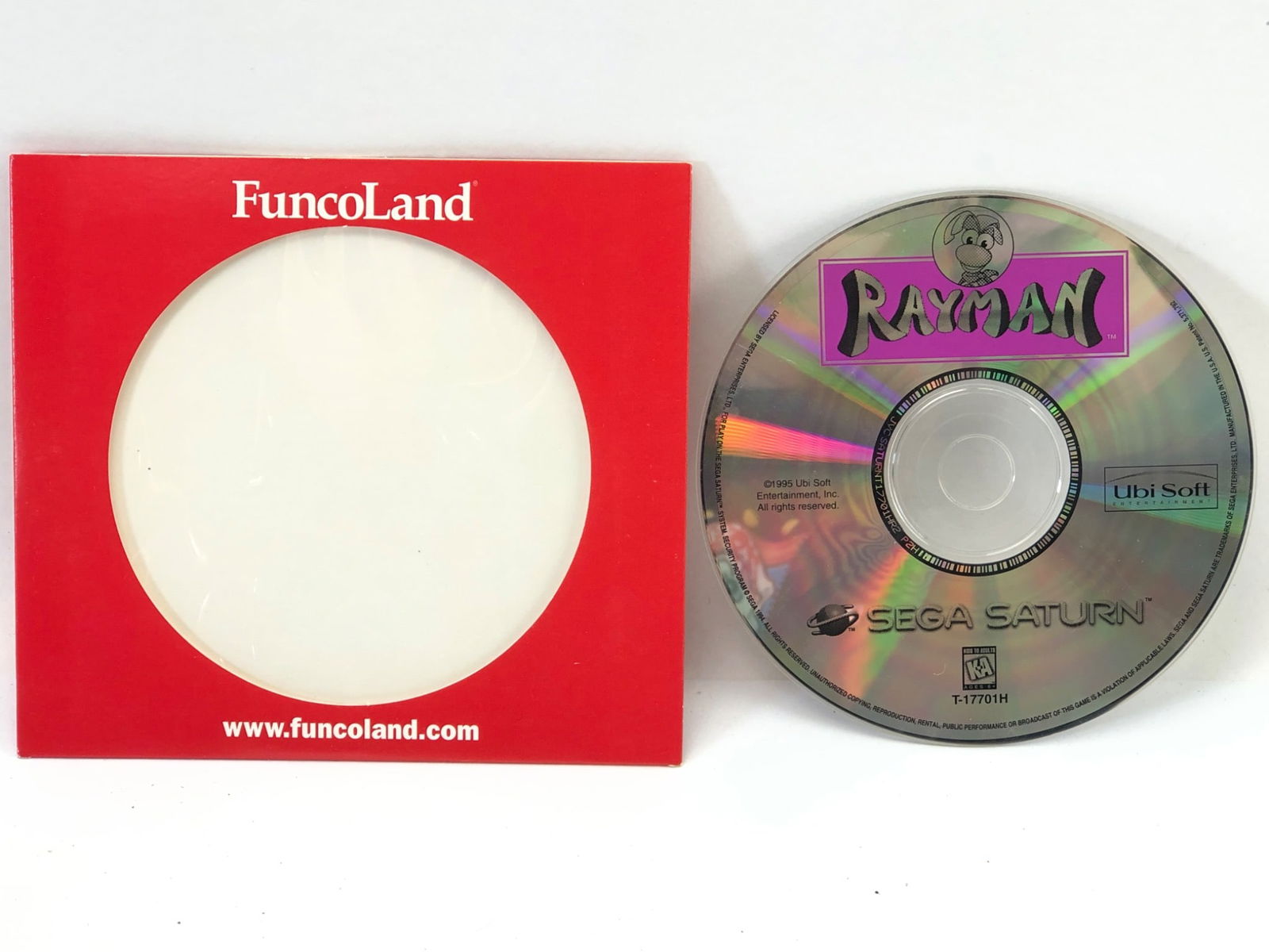 Rayman Sega Saturn Game Disc & FuncoLand Sleeve: Rayman video game disc for Sega Saturn by Ubi Soft, dated 1995. Includes a FuncoLand red paper sleeve with window. Some scratches present on the disc surface. Sold as is due to visible wear.