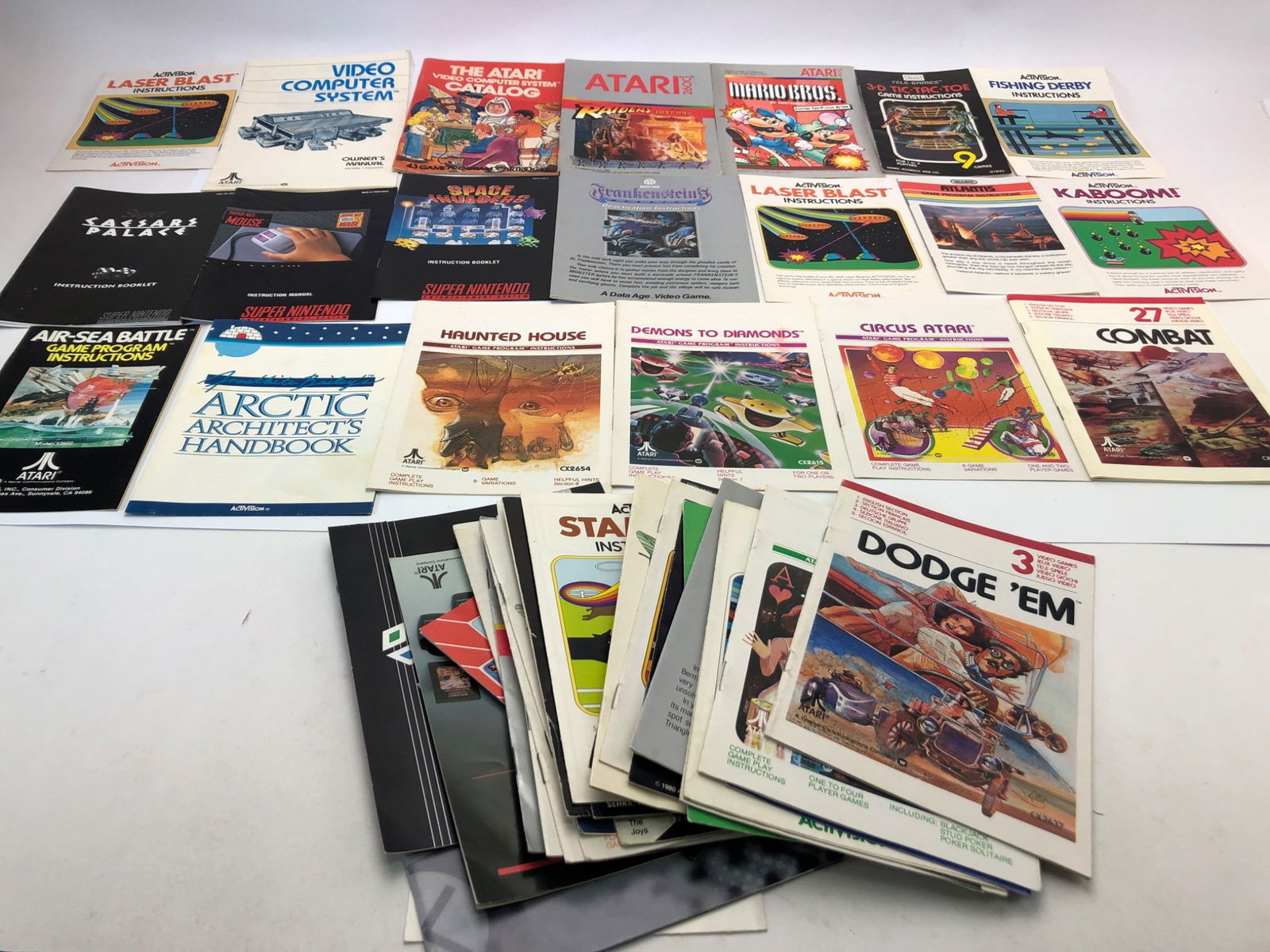Game Manuals & More Lot Featuring Atari & Activision: Various game manuals featuring Atari, Activision, and other classic gaming brands. Includes titles such as Dodge 'Em, Kaboom, Haunted House, and Starmaster. Assorted manuals for video games from vinta
