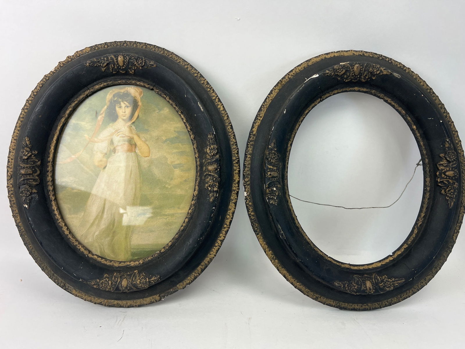 Victorian Gesso Frames With Portrait Prints: Victorian-era oval frames, 14.5? tall x 12? wide, featuring gesso detailing. One frame contains a print of a young girl, while the other is empty. Both frames exhibit notable gesso wear & chipping, wi