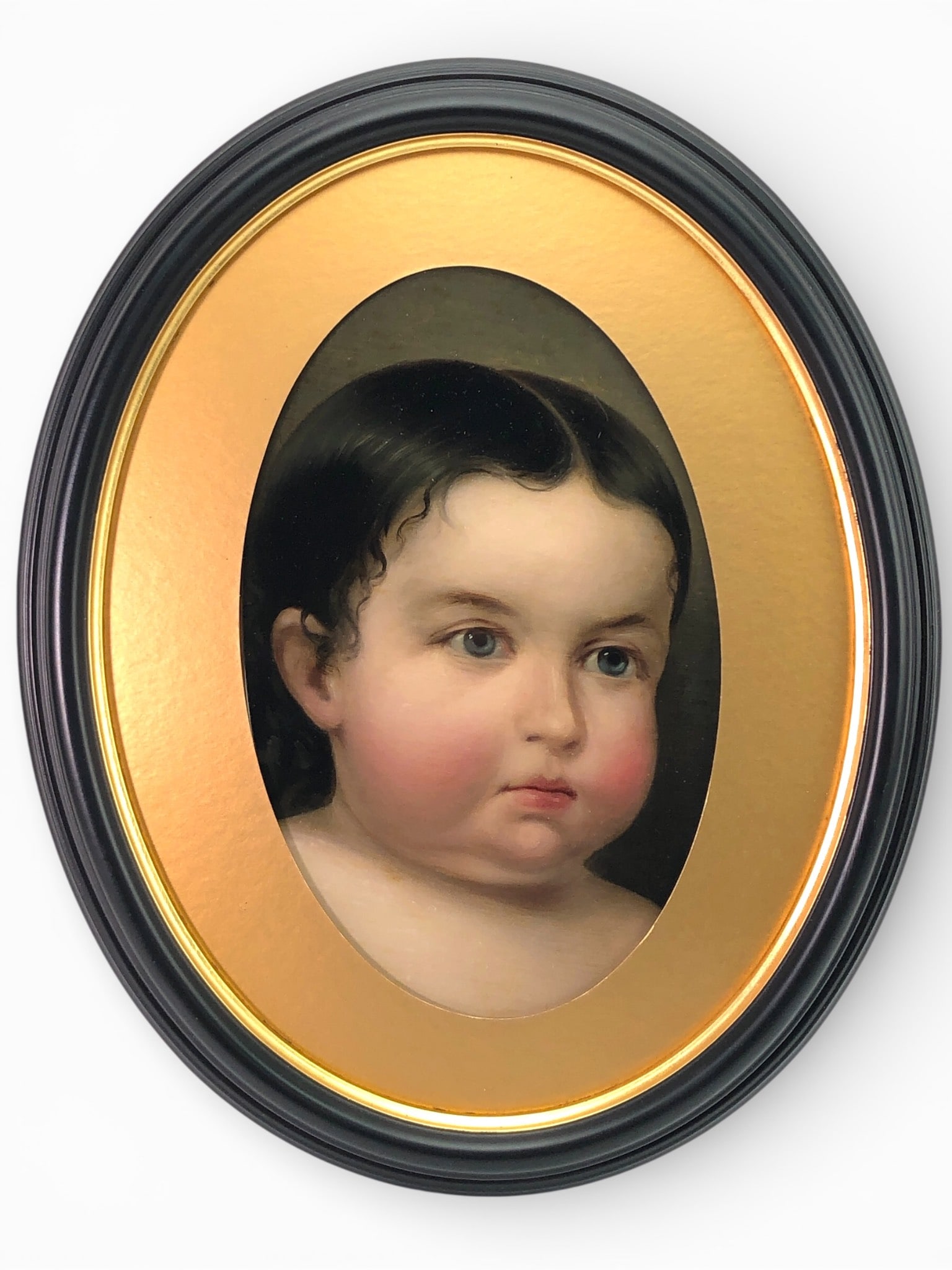 Antique Portrait Of Child In Oval Frame: Antique painting featuring a portrait of a child in an unsigned oval frame. The art is displayed in a 13 x 16-inch black & gold oval frame. The frame combines painted and gilded finishes with visible